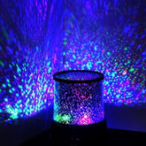 colorful star projector lamp illuminating a wall with vibrant star patterns and colors at night.